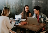 three people sitting in front of table laughing together