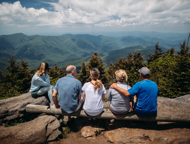 group of people sitting on rocks overlooking mountain