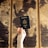 A hand is holding a United States passport in front of a blurred background showing a vintage-style world map with sepia tones.