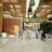 A modern airport terminal with an 'International departures' sign displayed prominently in multiple languages. The architectural design features a high ceiling with decorative plants hanging from above and polished stone flooring. Security personnel and travelers are visible near the entrance gates, and there is a blend of natural and artificial lighting.