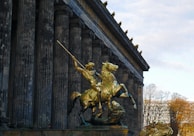 A statue of a man on a horse in front of a building